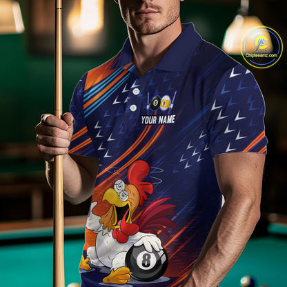 A man in a pool hall wearing a custom blue polo shirt with a cartoon rooster and 8-ball graphic, holding a pool cue. The shirt features a colorful design with orange, white, and blue patterns and the text 'YOUR NAME'.