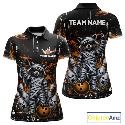 Custom short-sleeve polo shirt shown from front and back on a white background. The shirt features a black base with orange paint splatter graphics and a detailed graphic of a raccoon wrapped in bandages holding bowling balls.