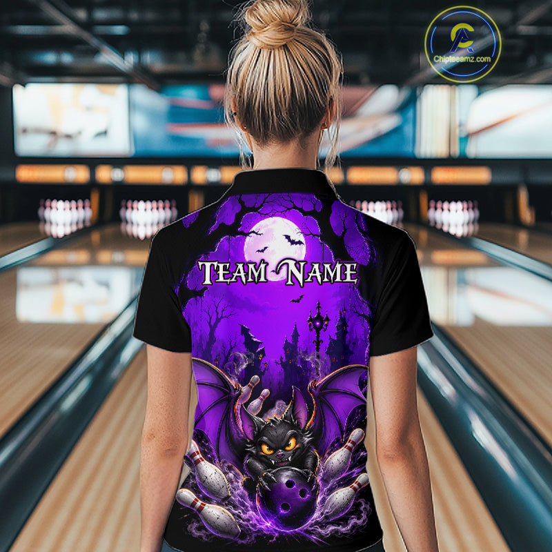 A woman viewed from behind wearing a black short-sleeve bowling shirt with a large purple Halloween graphic on the back, featuring a bat, full moon, haunted house, and a bat biting bowling pins. The shirt has 'TEAM NAME' printed across the upper back.