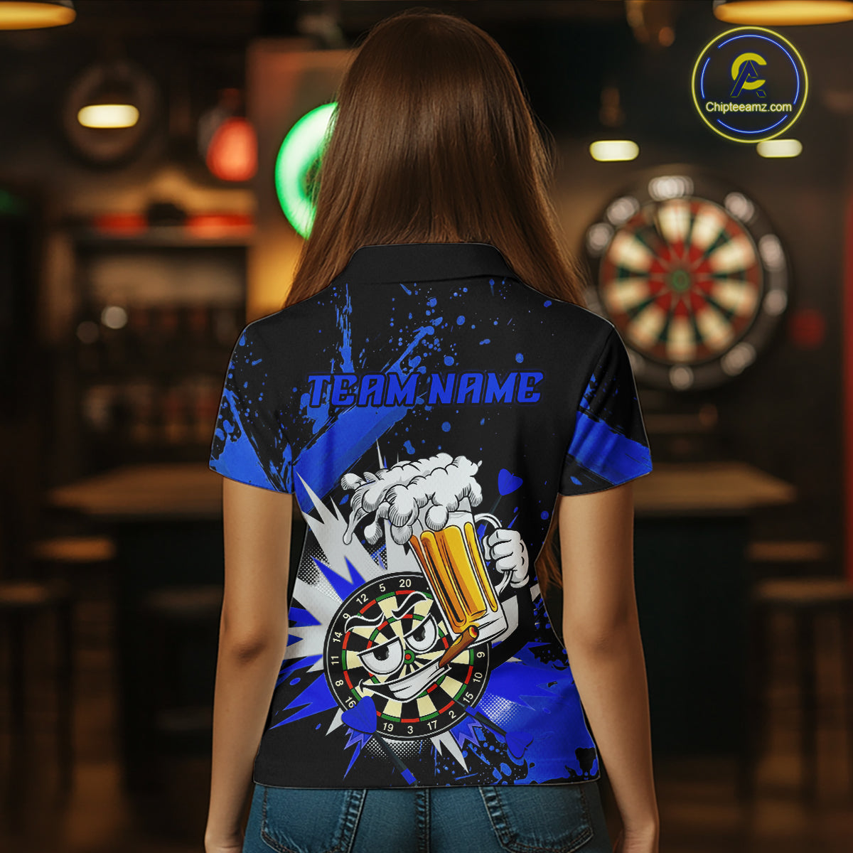 A woman viewed from behind wearing a short-sleeve black and blue graphic polo shirt with a cartoon beer mug and dartboard design on the back, standing in a dimly lit bar with a dartboard visible in the background.