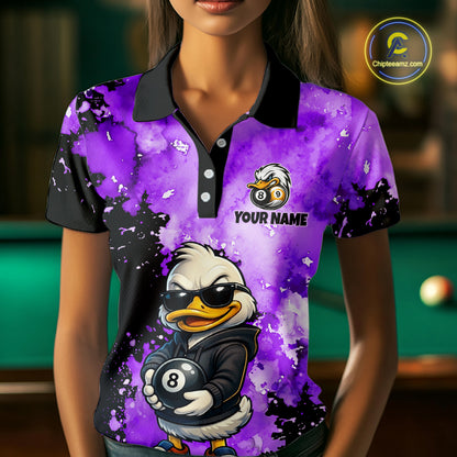 A woman wearing a purple and black short-sleeve polo shirt with a cartoon 8-ball duck graphic and the text 'YOUR NAME' on the chest. The shirt has a watercolor splatter design, black collar and sleeves, and a white logo on the left chest.