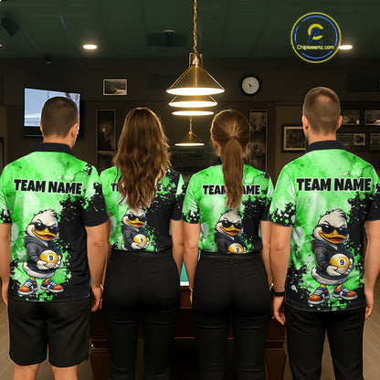 Four people standing with their backs to the camera wearing matching custom short-sleeve athletic shirts in a dimly lit indoor venue. The shirts are bright green and black with a cartoon duck graphic and the text 'TEAM NAME' across the upper back.