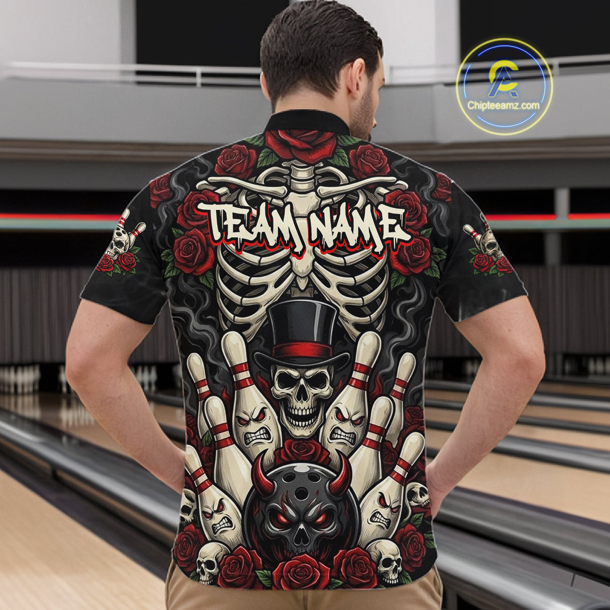 A man viewed from behind wearing a black short-sleeve button-up shirt with a large back graphic featuring a skeleton, skulls, roses, bowling pins, and the text 'TEAM NAME'. The background shows a bowling alley interior.