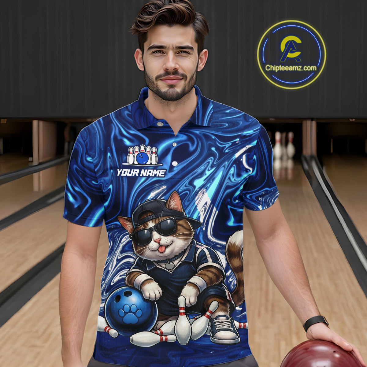 Man wearing a blue bowling-themed shirt with a cat design in a bowling alley.