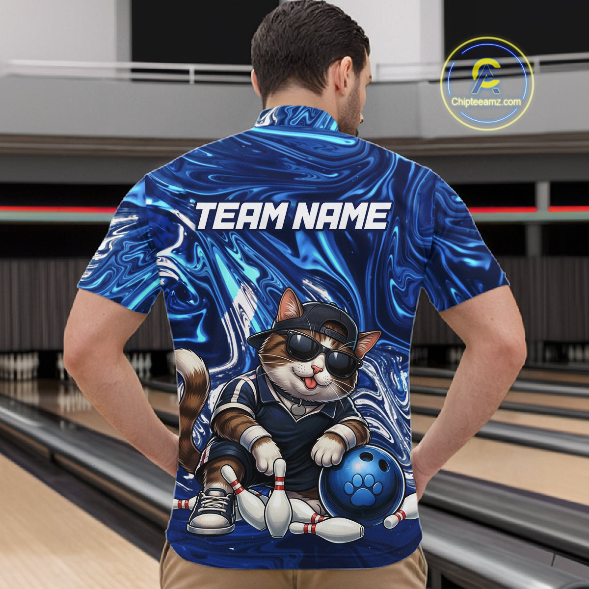 Person wearing a blue bowling-themed shirt with a cat design in an indoor setting, likely a bowling alley.