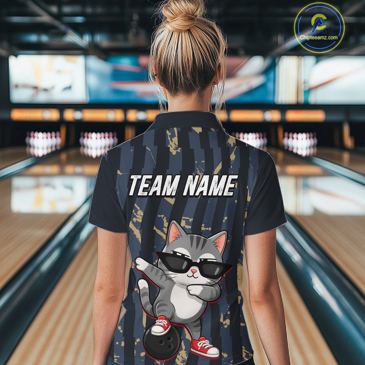 Person wearing a shirt with a cat graphic and 'TEAM NAME' text in a bowling alley.
