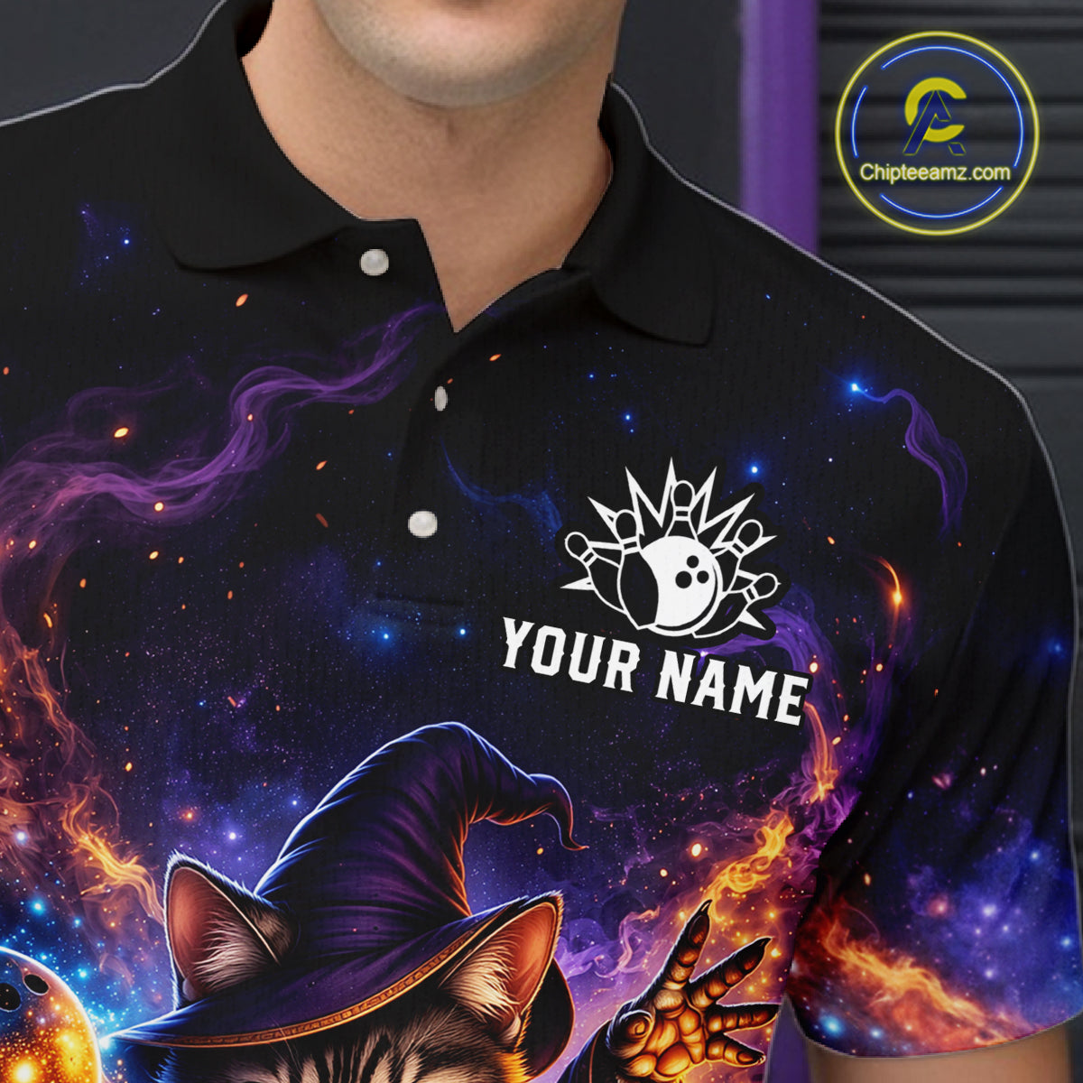 Black polo shirt with a colorful design featuring a cat in a witch hat, flames, and space-themed elements. The brand 'Chipteeamz.