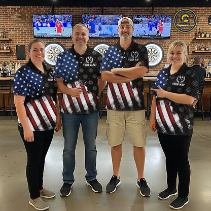 Group of darts players wearing matching custom black polo shirts with distressed US flag graphics, posing together in a sports bar setting