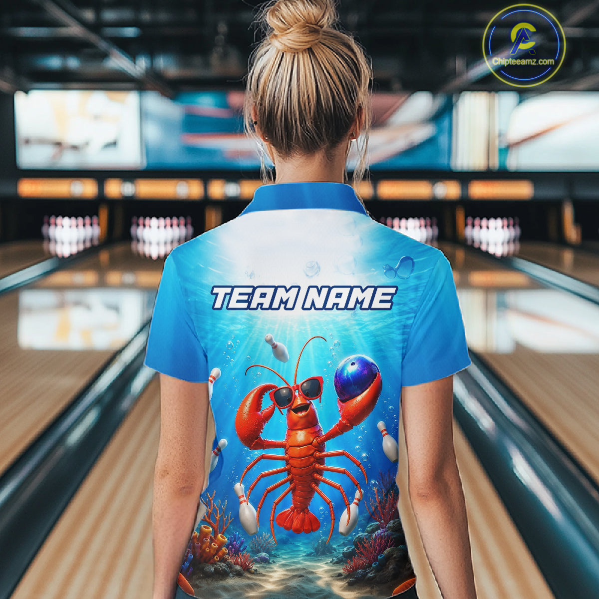 Person wearing a blue bowling shirt with a lobster design and 'TEAM NAME' text in a bowling alley.