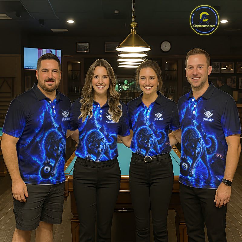 Four people standing together in a dimly lit indoor venue, wearing matching dark blue polo shirts with a glowing blue cosmic or nebula-style graphic print and black pants. A pool table is visible behind them