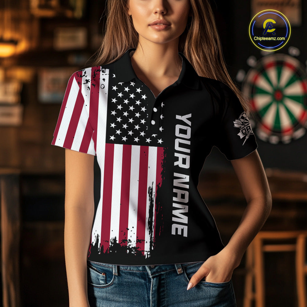 A woman wearing a custom patriotic dart polo shirt featuring a distressed American flag graphic in a professional dart room.