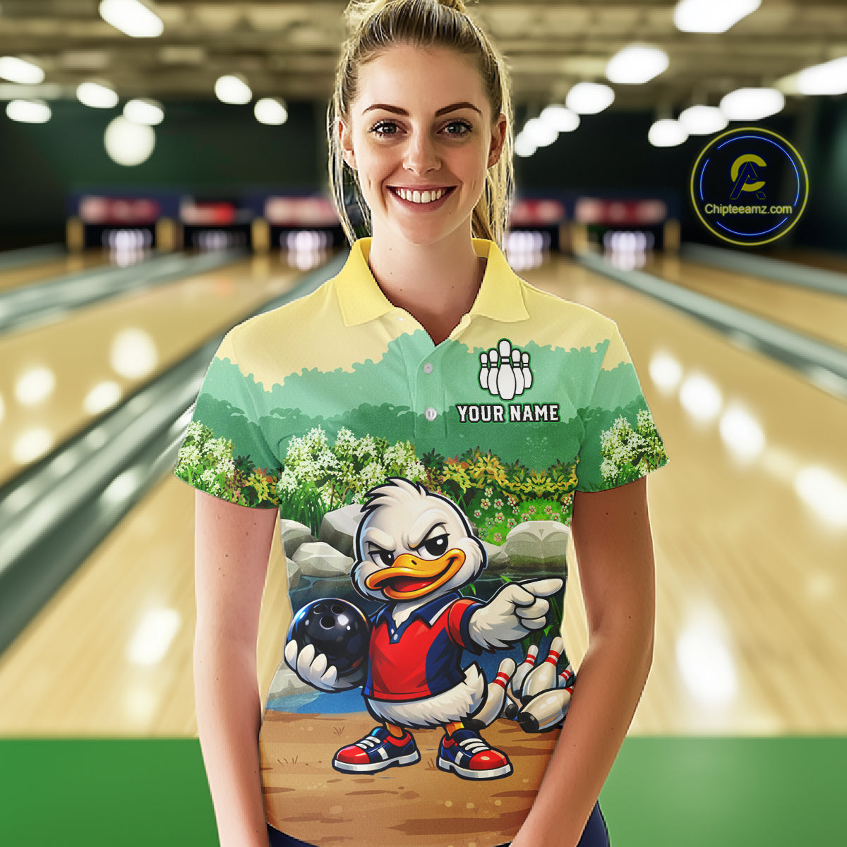 Woman wearing a bowling-themed shirt with a cartoon duck character in a bowling alley.