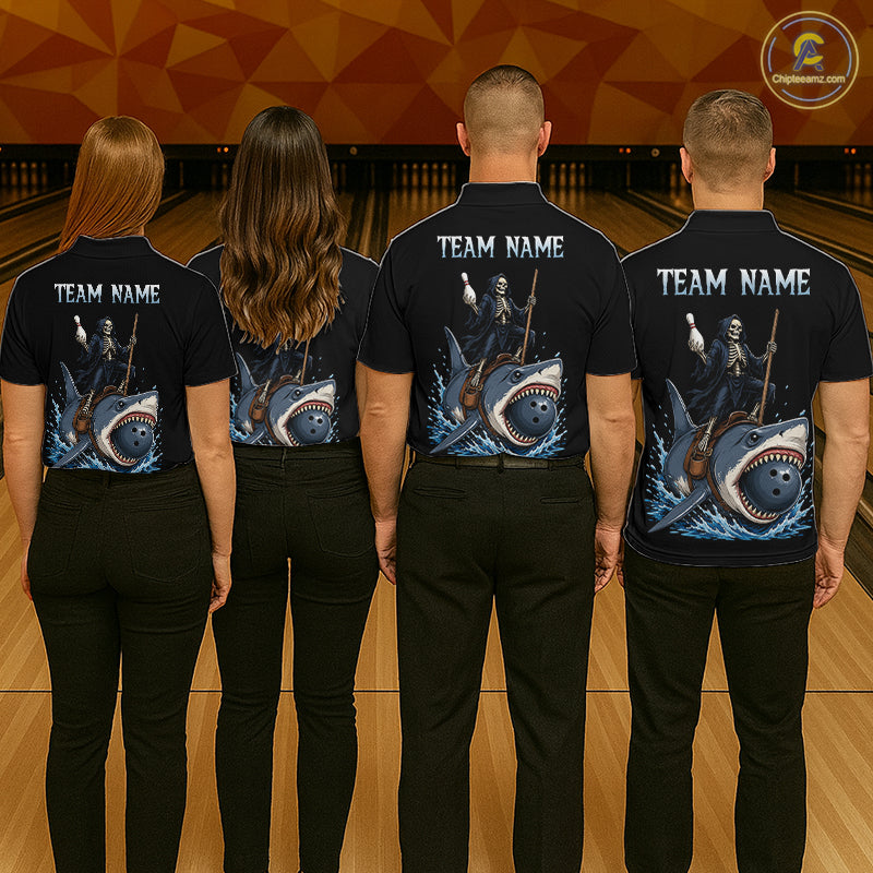 Four people standing in a bowling alley, viewed from behind, wearing matching black short-sleeve polo shirts with a large shark-and-whale graphic on the back and white 'TEAM NAME' text. The shirts also show skeleton divers holding ping-pong paddles.