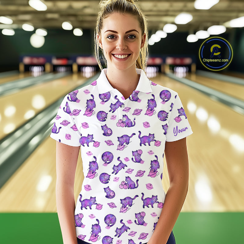 Woman wearing a white polo shirt with purple cat pattern in a bowling alley.