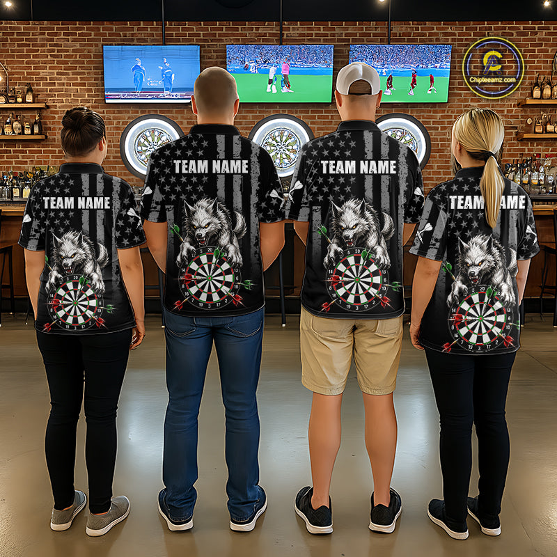 Four people standing with their backs to the camera in a bar setting, wearing matching black short-sleeve shirts with a large graphic of a wolf, dartboard, and American flag design, along with customizable text 'TEAM NAME' on the back.