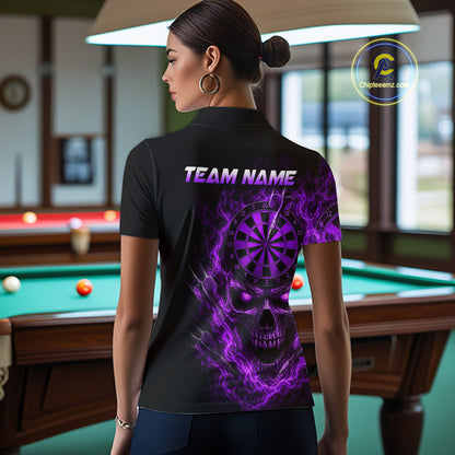 A woman stands in a billiards room wearing a black short-sleeve polo shirt with a large purple and black skull graphic and the text 'TEAM NAME' on the back. A pool table is visible in the background.