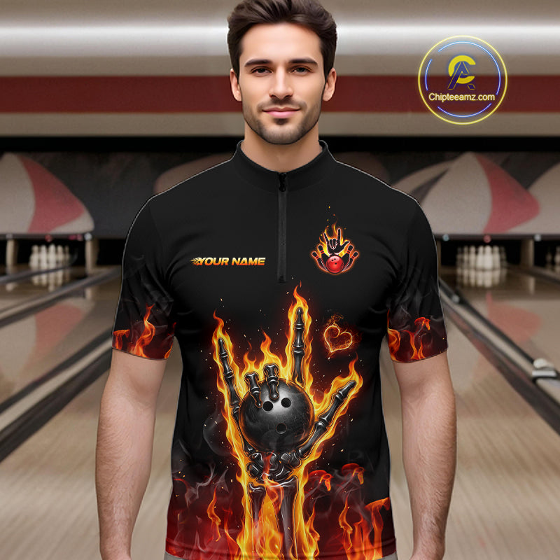 A man wearing a black short-sleeve zip-front cycling or athletic jersey with a bold flame and bowling-ball graphic on the front, standing in a bowling alley. The jersey has 'YOUR NAME' printed on the chest.