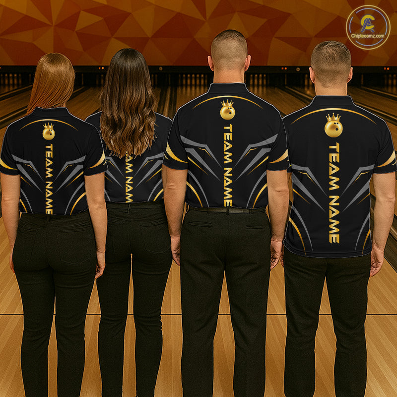 Four people standing in a bowling alley, viewed from behind, wearing matching dark navy short-sleeve team shirts with gold and gray graphic details and black pants. The shirts have vertical 'TEAM NAME' text and a circular logo on the upper back.