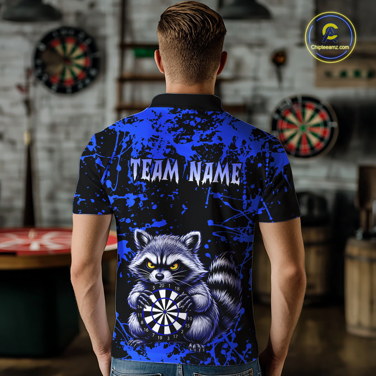 Person wearing a blue and black polo shirt with a raccoon graphic and 'TEAM NAME' text, in a room with dartboards.