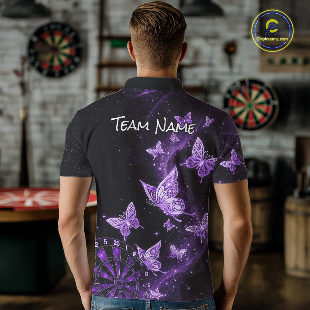A man viewed from behind wearing a dark gray short-sleeve polo shirt with a purple butterfly and starry galaxy print, featuring the text 'TEAM NAME' on the back. The background is a blurred indoor room with dartboards.
