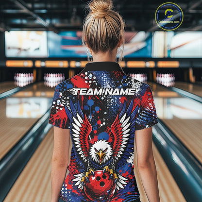 Back view of a woman in a bowling alley wearing a custom team jersey with red, blue, white, and black splatter graphics, â€œTEAM NAMEâ€ text, and a large eagle clutching a red bowling ball.