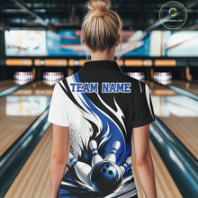 Load image into Gallery viewer, Back view of a female model wearing a white, black, and blue bowling polo shirt with a flaming bowling ball knocking down pins graphic at a bowling lane.