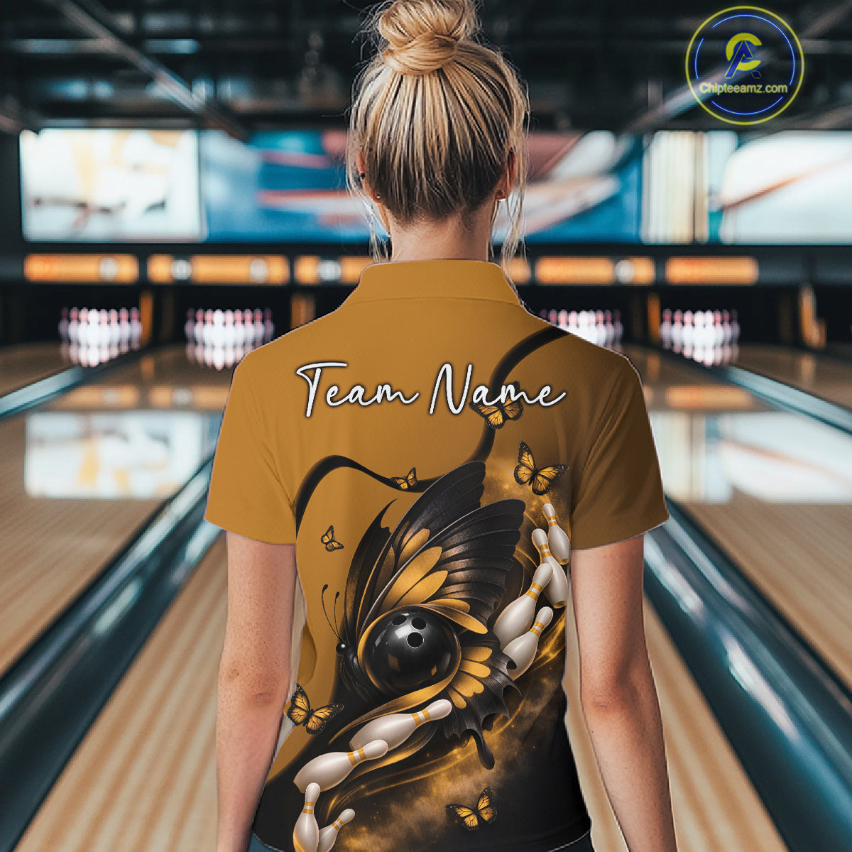 Back view of a female model at a bowling lane wearing a yellow and black bowling quarter-zip shirt featuring a butterfly wrapped around a bowling ball.