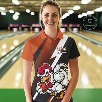 A woman stands in a bowling alley wearing a custom-designed polo shirt with a bold graphic print featuring cartoon chickens and a white lightning bolt. The shirt has orange sleeves, a black right side, and a white center stripe.