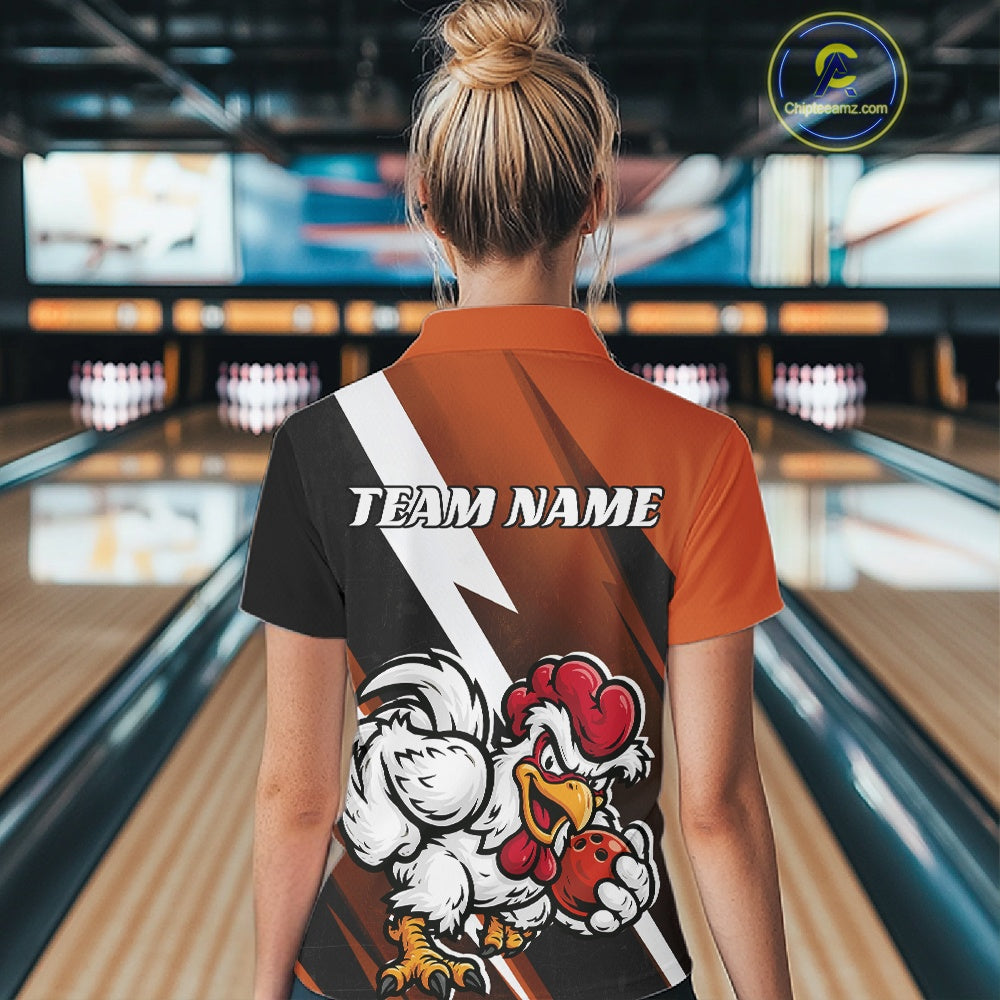 A woman viewed from behind wearing a custom short-sleeve polo shirt in a bowling alley. The back of the shirt features a black, orange, and white graphic design with a lightning bolt, the text 'TEAM NAME', and a cartoon rooster holding a bowling ball.