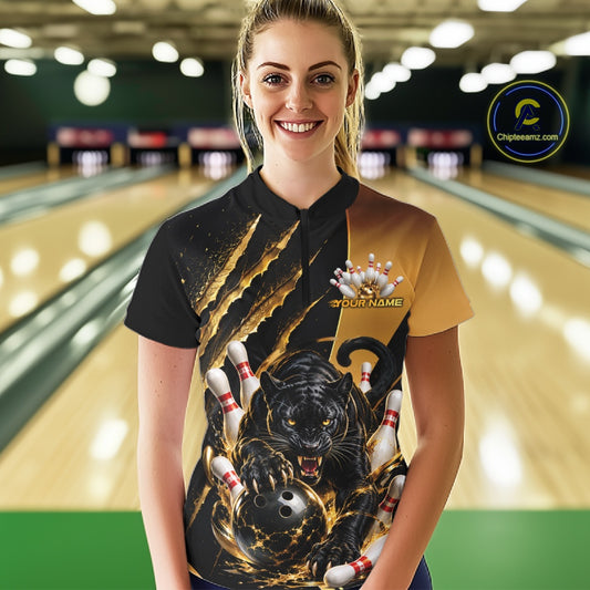 A woman stands in a bowling alley wearing a custom bowling shirt with a black and gold design featuring a black panther, bowling balls, and pins. The shirt has a split black and gold color scheme with a graphic print on the front.