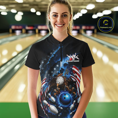 Female model front view in a bowling lane wearing a quarter zip shirt with bald eagle artwork, blue bowling ball, flying pins, and flag background.