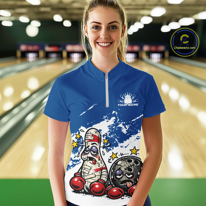 Female model at a bowling lane wearing a blue and white quarter-zip shirt, cartoon boxing bowling ball and pin artwork with energetic feel.