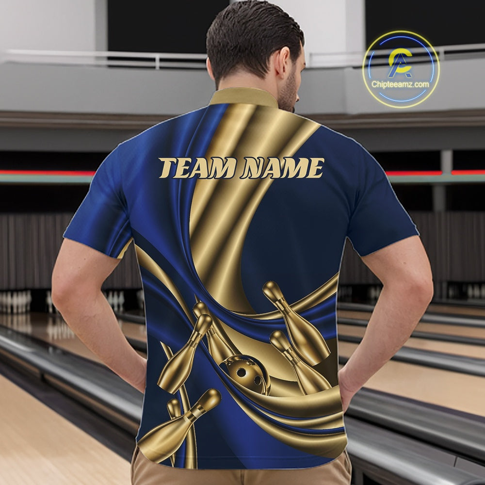 A man viewed from behind wearing a custom bowling-themed short-sleeve shirt with a blue and gold satin-wrapped design, bowling pins, and the text 'TEAM NAME' on the back. The background shows a blurred bowling alley interior.