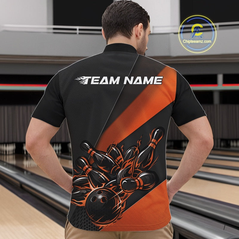 At the bowling lane, front view of a male model wearing a black and orange quarter zip featuring a flaming bowling strike scene with pins scattering in motion.