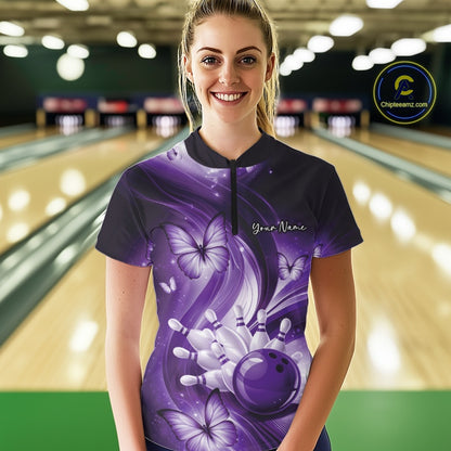 Female model in a bowling center wearing a purple quarter-zip with bowling strike and butterfly illustrations.