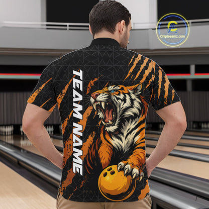 Front view of a male model at a bowling lane wearing a black and yellow bowling quarter-zip shirt featuring a roaring tiger holding a yellow bowling ball with orange claw-stripe artwork and a geometric background pattern.