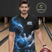 Load image into Gallery viewer, Front view of a male model in a bowling alley wearing a black bowling polo shirt featuring a blue fiery skull with lightning striking a bowling ball and pins and a custom name.
