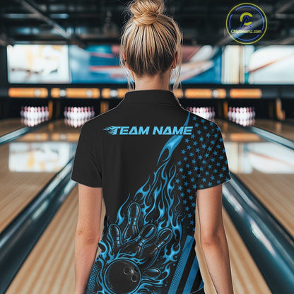 Back view of a female model in a bowling alley wearing a black quarter-zip shirt featuring a blue flaming bowling ball hitting the pins.