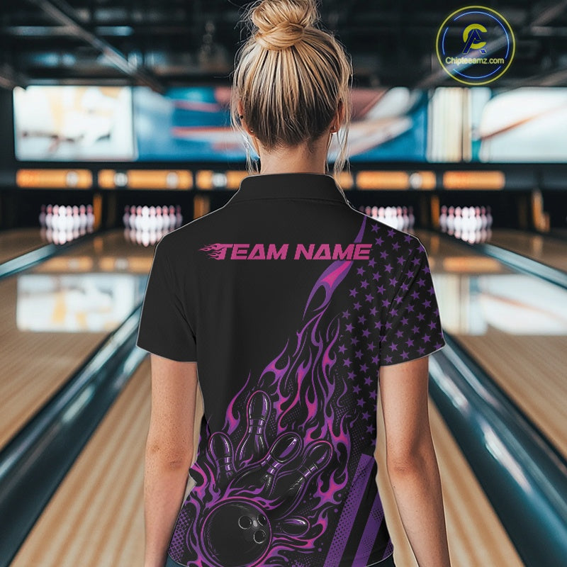 Back view of a female model in a bowling center wearing a black quarter-zip shirt showcasing a flaming bowling ball and patriotic pin graphics.