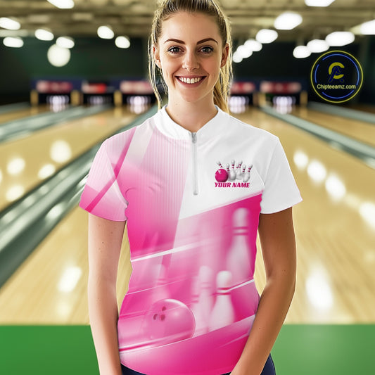 Front view female model at the bowling lane wearing a white and pink quarter zip shirt with bowling ball and pins geometric artwork.