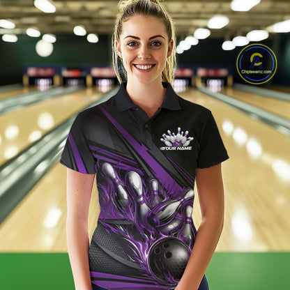 Female model in a bowling lane, front view wearing black polo shirt with purple flame bowling ball hitting pins and geometric stripe graphics
