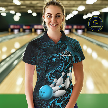 Female model standing in a bowling lane wearing a black and blue bowling polo shirt featuring a tribal flame bowling ball and pins graphic on the front.