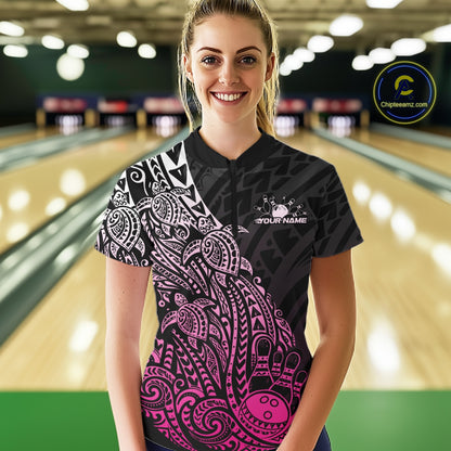 Female model wearing a black and pink bowling quarter-zip shirt at the bowling lane with Polynesian-style bowling artwork.