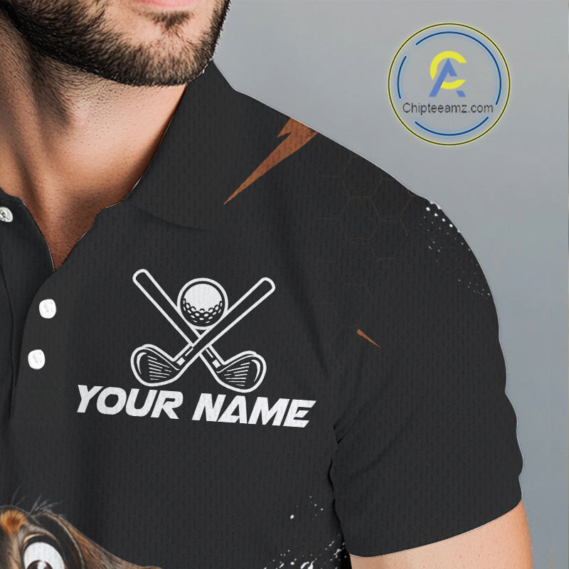 A close-up of a man wearing a black short-sleeve polo shirt with a white golf-themed chest graphic featuring crossed clubs, a golf ball, and the text 'YOUR NAME'.