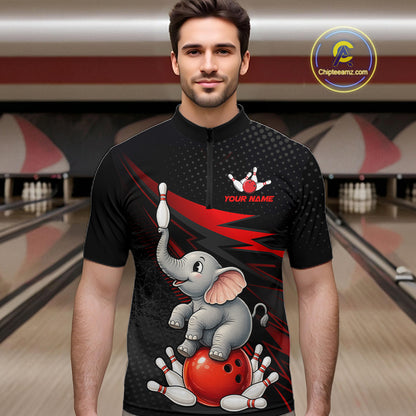 A man wearing a black short-sleeve quarter-zip bowling-themed t-shirt with a cartoon elephant, red bowling ball, and white pins printed on the front. The background shows a blurred bowling alley with lanes and pins.