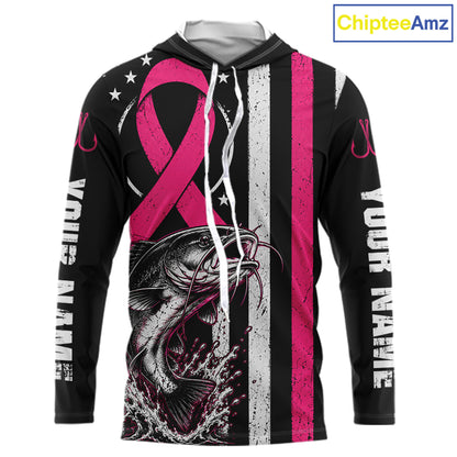 A black long-sleeve hoodie with a pink and white distressed design featuring a large pink ribbon, a fish graphic, white stars, and vertical text on the sleeves. The hood is open, showing a gray interior lining.
