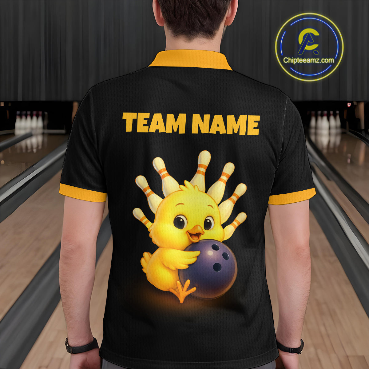 Person wearing a black shirt with a cartoon chicken holding a bowling ball and 'TEAM NAME' text, in a bowling alley setting.