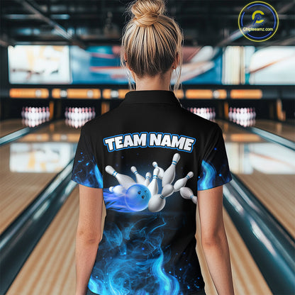 Person wearing a black bowling shirt with a blue and white design in a bowling alley.